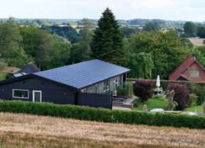 Solartag på sort træhus i kuperet landskab i Vejle området